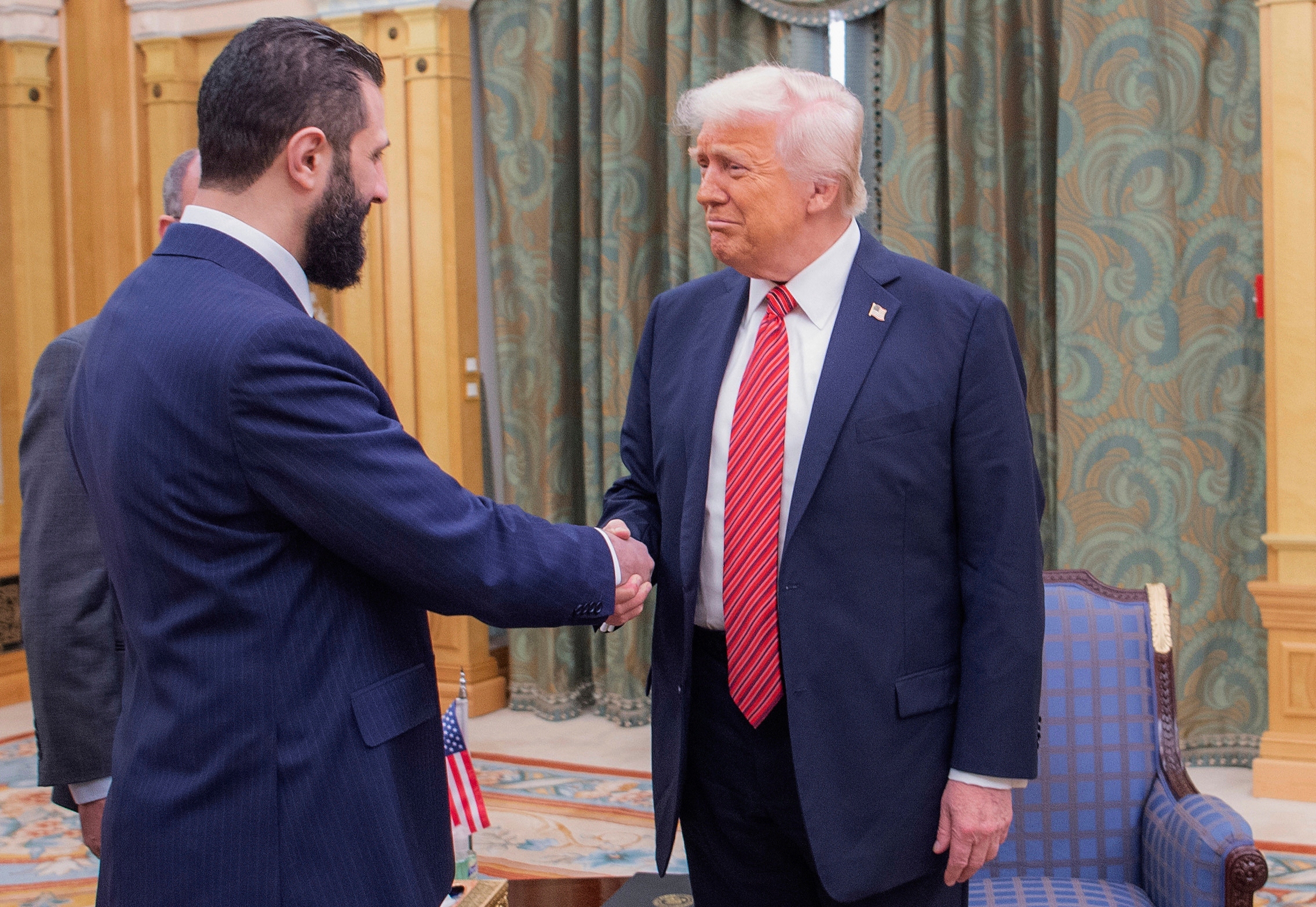 In this photo released by the Saudi Royal Palace, President Trump shakes hands with Syria